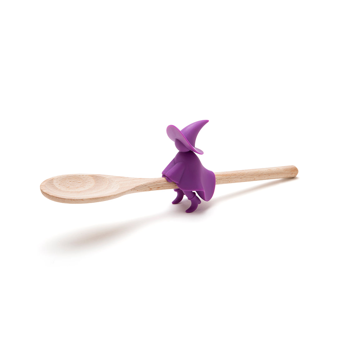 Agatha, the purple witch figure, sits on a wooden spoon holder with a plain white background.