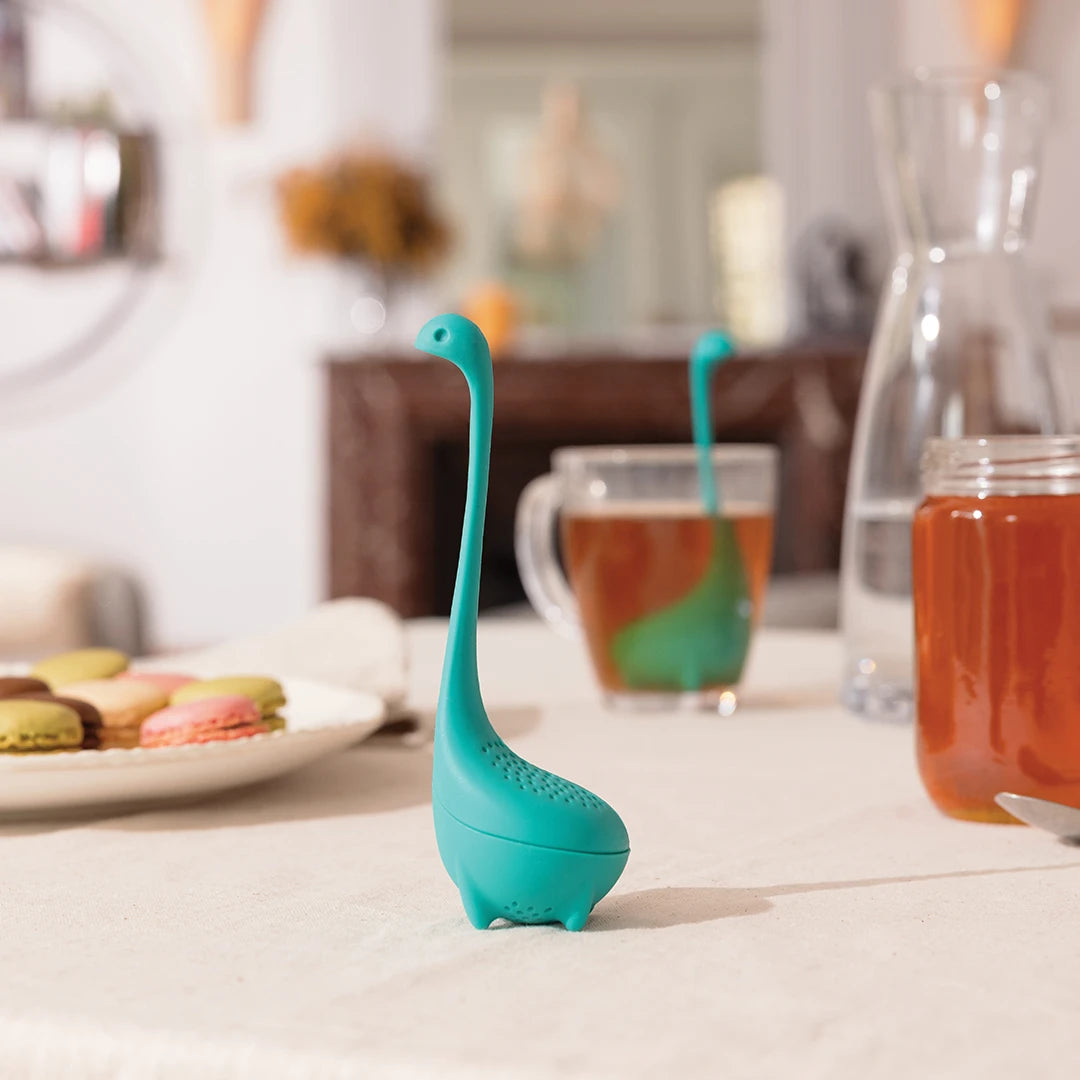 Baby Nessie on a table with tea, macarons, and a glass pitcher.