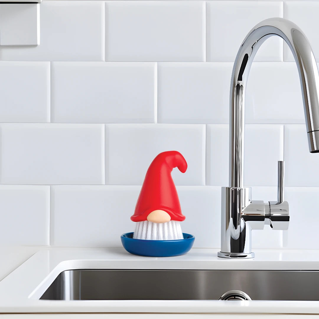 OTOTOs Beardy dish brush adds fun to kitchen chores by the sink with a white tiled backsplash.