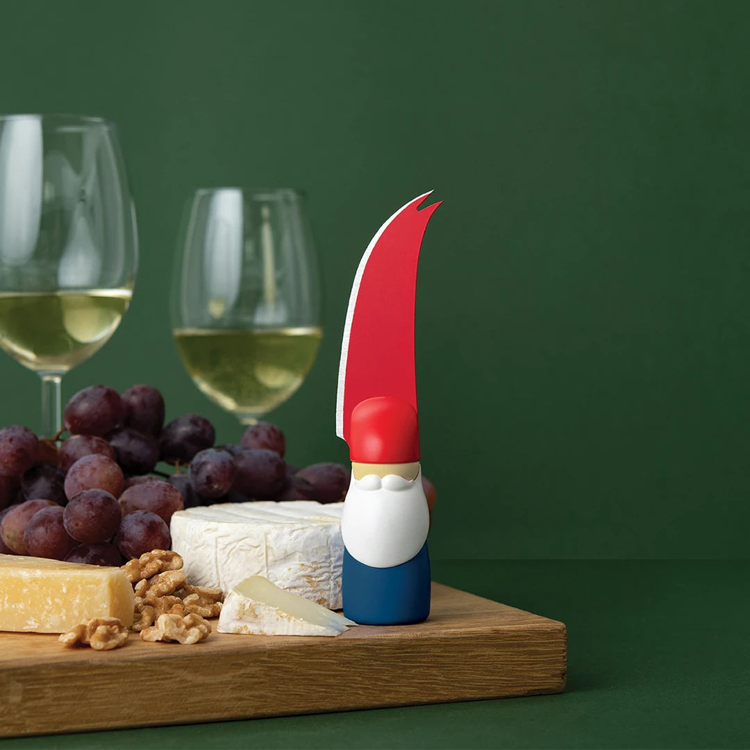 Bert OTOTO cheese knife on a board with cheese, grapes, walnuts; two glasses of white wine behind.
