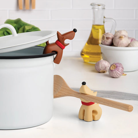 Best Buddies dog-shaped pot holders, one with lid, another as spoon holder, on a white counter.