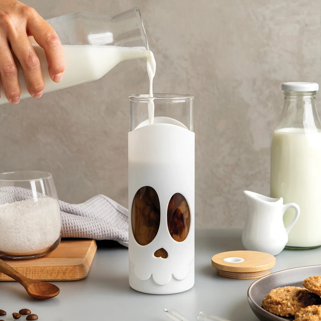 Pouring milk into a Bonesy glass, surrounded by coffee beans and breakfast treats.