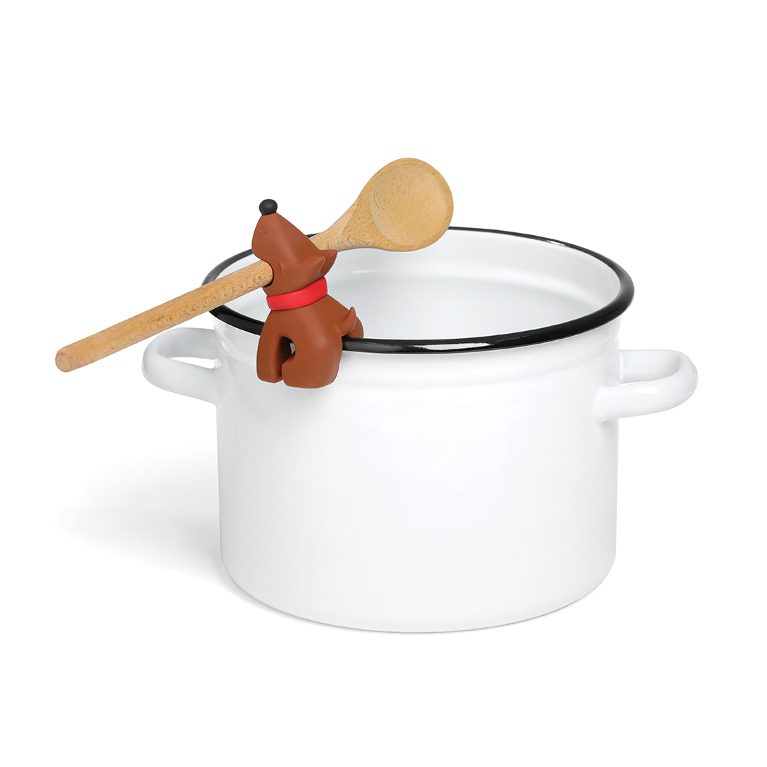 Buddy spoon with dog-shaped steam releaser resting on a white pot with handles.