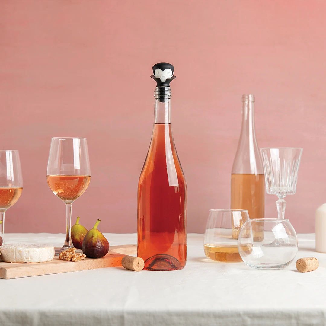Indulge like a wine-loving vampire with Count Corkulas glasses, figs, cheese, and nuts against pink.