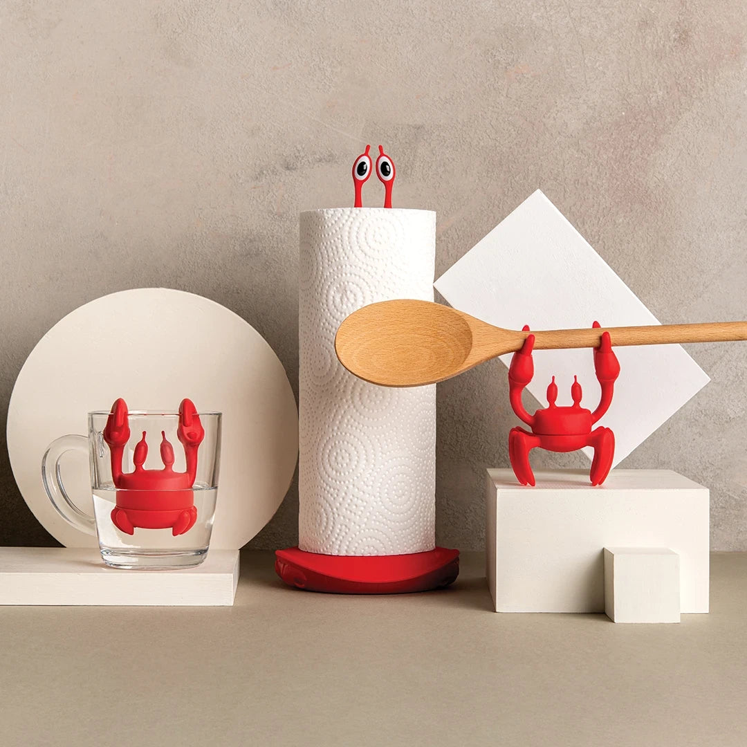 Red Crab Tea-themed kitchen tools: cup holder, paper towel holder, and spoon rest on geometric blocks.