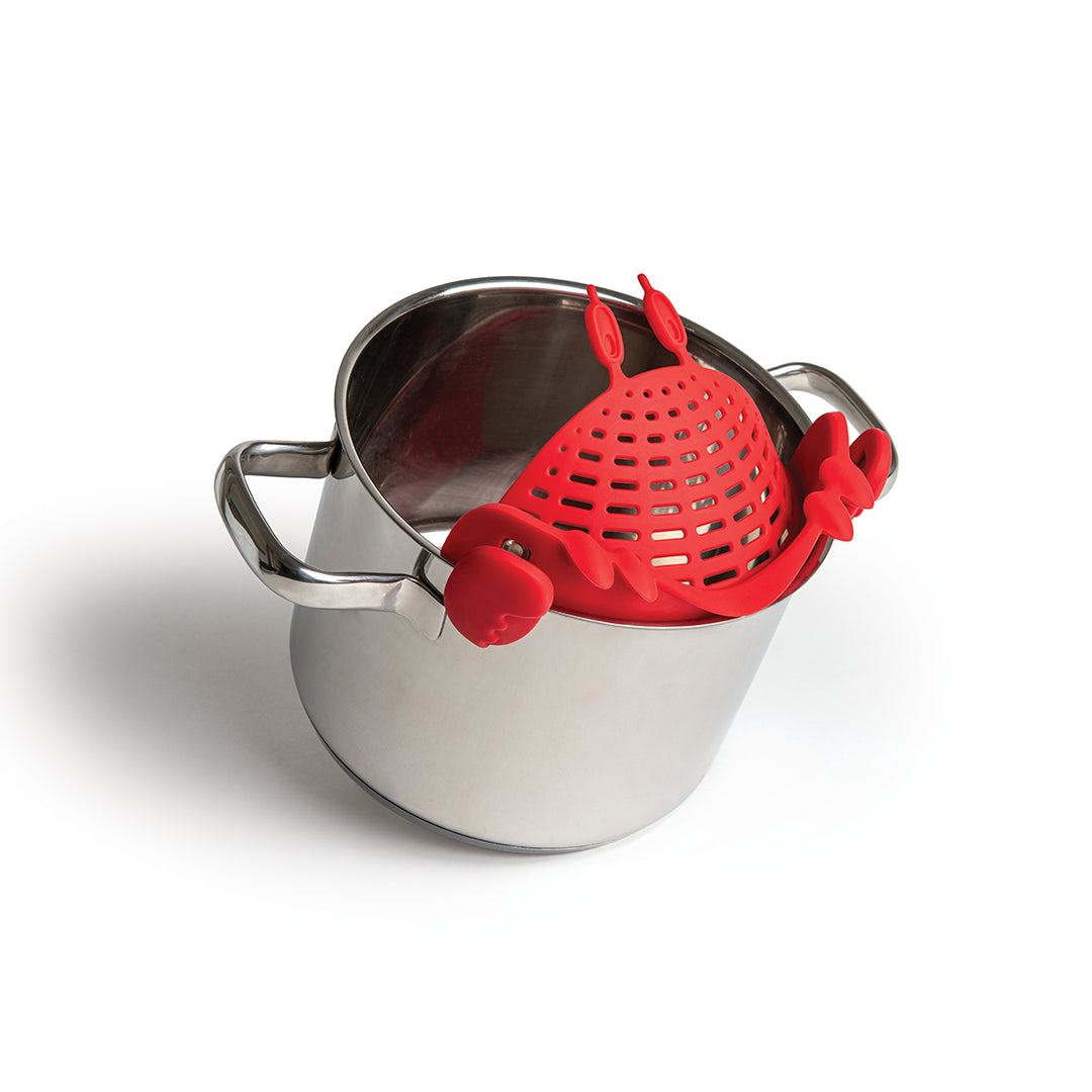The Crabby pasta strainer, an OTOTO kitchen accessory, clips onto a stainless steel pot on a white background.
