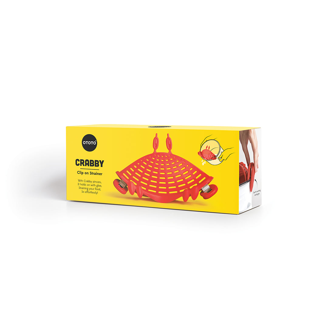 Yellow box featuring Crabby pasta strainer, plus hand showing its use with OTOTO design.