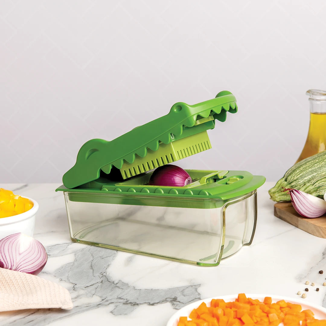 Croc Chop green croc-shaped slicer with onion and chopped veggies sits on the counter.