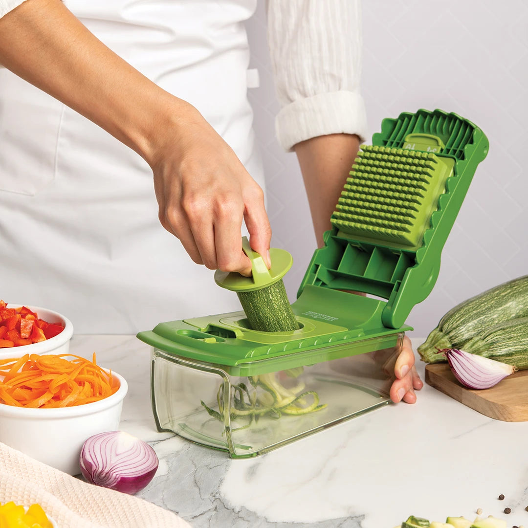 A person spiralizing zucchini with a Croc Chop, surrounded by chopped vegetables.