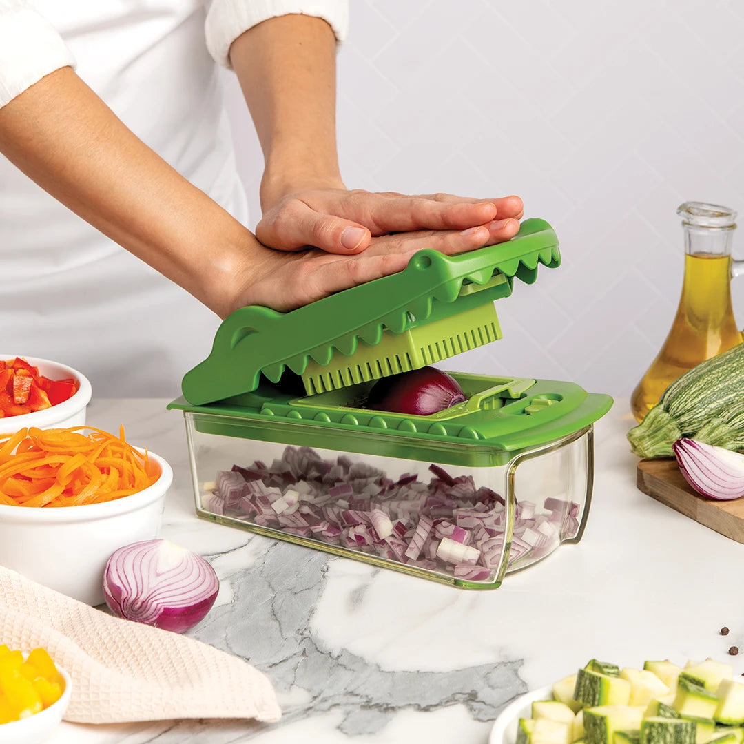 Person using a green vegetable chopper to dice an onion on a kitchen countertop.