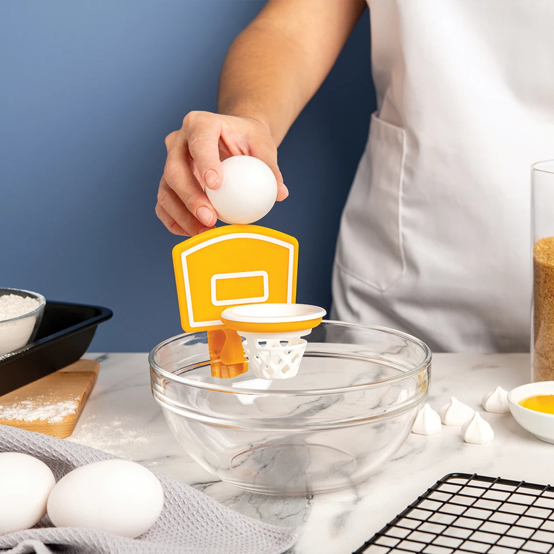 Cracking an egg through Dunk N Egg hoop over a bowl; this kitchen tool is versatile and easy to clean.