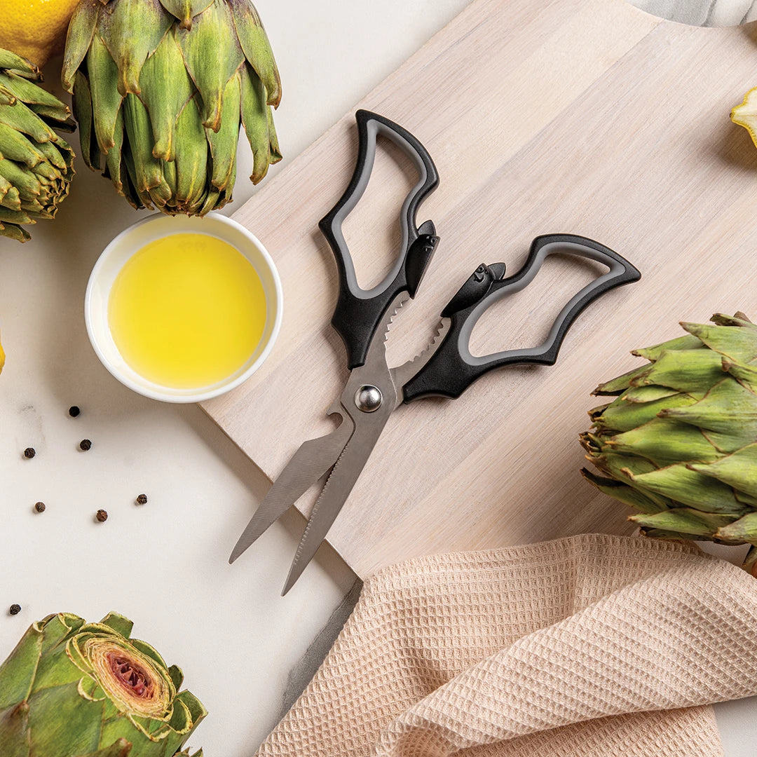 Elizabat scissors on a cutting board surrounded by artichokes, lemon juice, and black pepper.