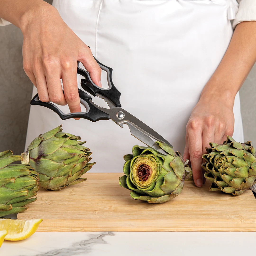 In a white apron, a person expertly trims artichokes with Elizabat scissors from OTOTO.