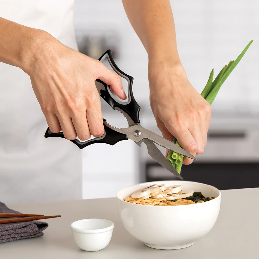 Person using the Elizabat kitchen scissors to cut green onions over soup.