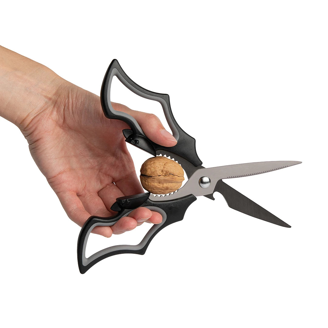 Using Elizabat kitchen scissors with a jagged edge to crack a walnut, isolated on white background.