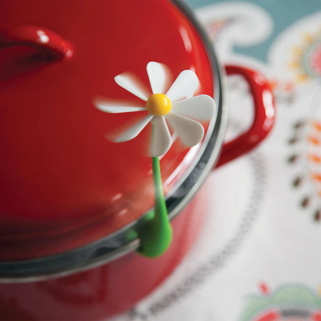 Flower Power red pot with daisy steam releaser on the lid, placed on a patterned tablecloth.