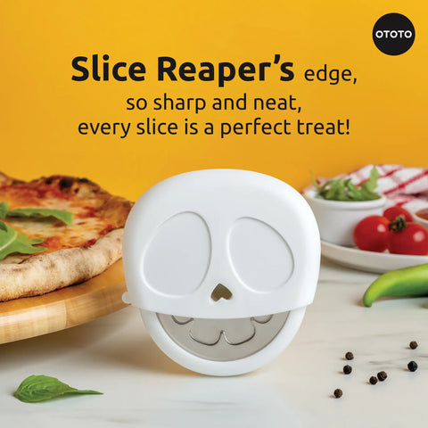 A Slice Reaper pizza cutter sits before a pizza, tomatoes, and peppers on the table.