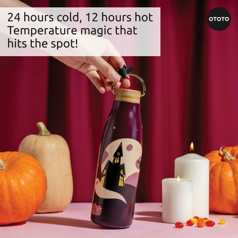 A hand holds an OTOTO Boo!tle insulated water bottle among pumpkins and candles, casting Halloween vibes.