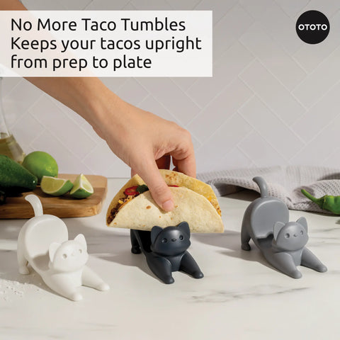Two Catos taco holders keep tacos upright on the counter near limes and utensils.