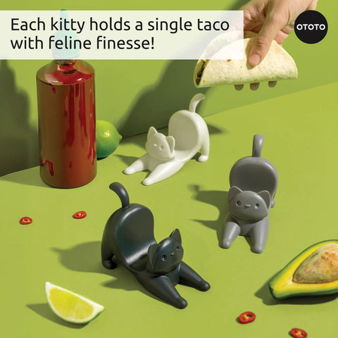 Three Catos taco holders by OTOTO display tacos on a green table with hot sauce, lime, and avocado.