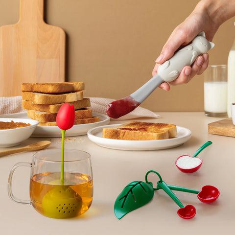 The Mary Cat spatula spreads jam beside a Tulip infuser and Mon Cherry leaf spoons.