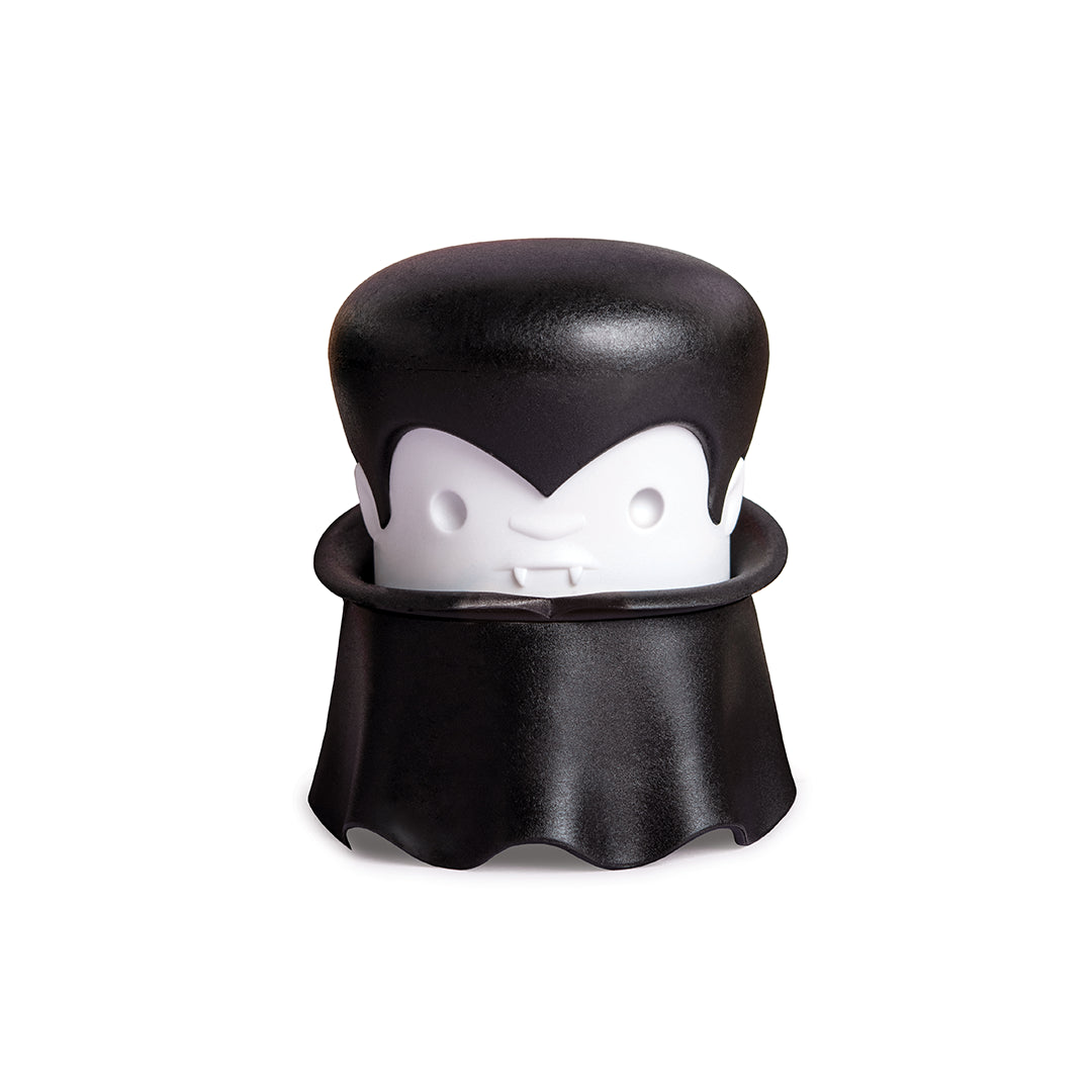A cartoon vampire with a cape and fangs holds an OTOTO Gracula garlic crusher.