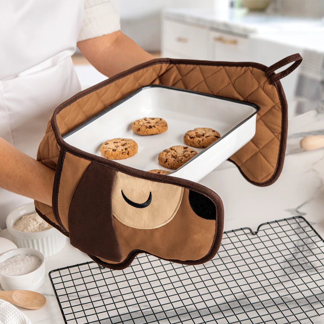 OTOTOs Hot-dog Mitts, shaped like dogs, hold a baking tray of cookies in the kitchen.
