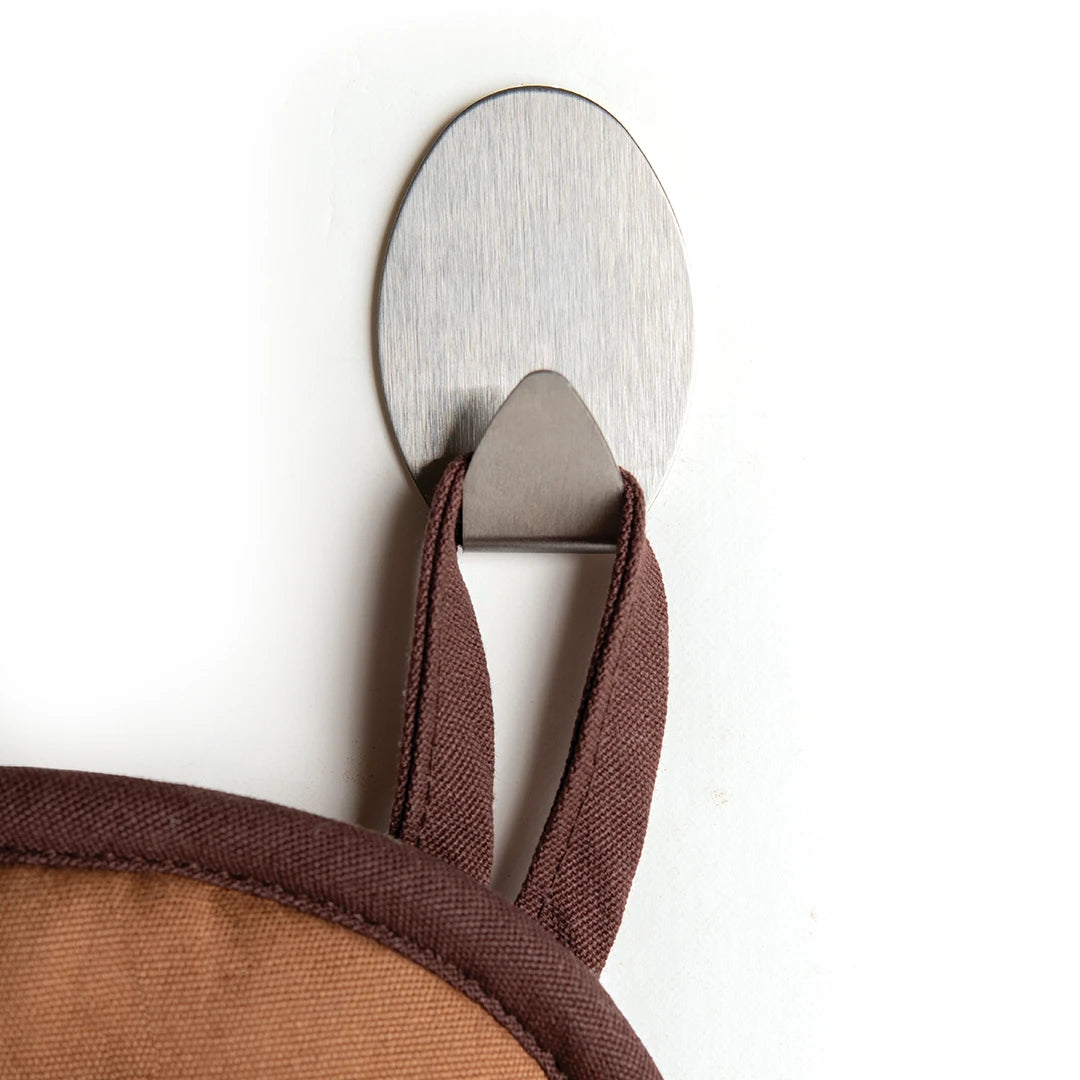Hot-dog Mitts hang on a silver wall hook against a light background.