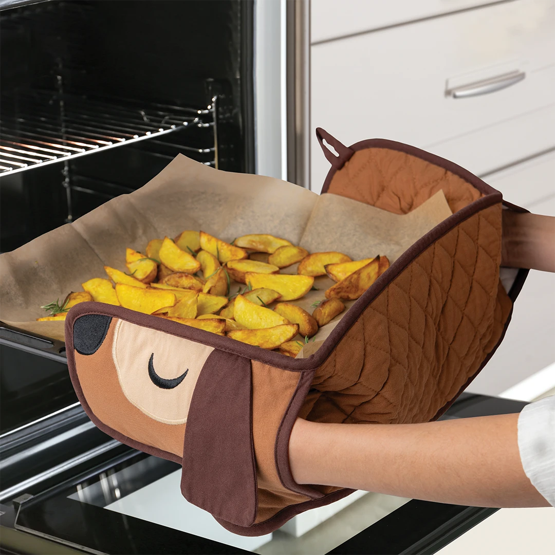 Person using dog-themed oven mitts to remove baked potato wedges from the oven.
