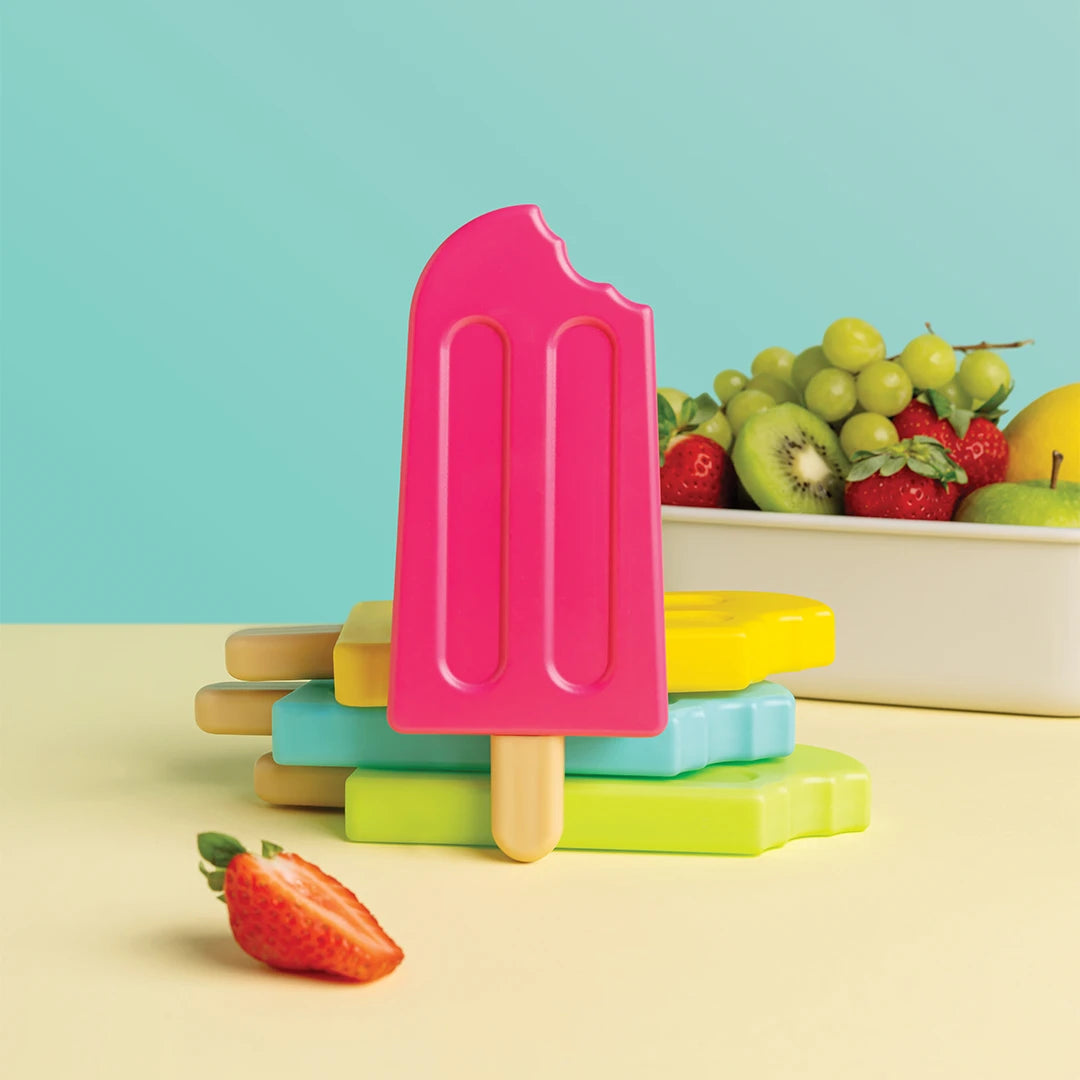 A bright pink OTOTO Ice Pop Ice Pack with a bite mark, stacked with colorful popsicle molds.