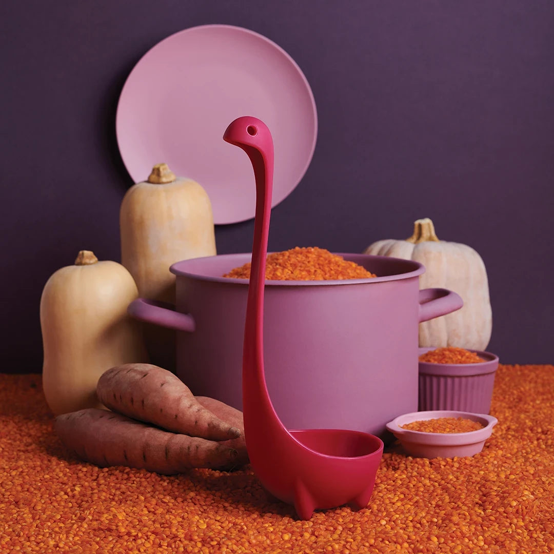 Jumbo Nessie (Purple), the dinosaur-shaped soup ladle by OTOTO, stands amid squash, yams, and lentils.