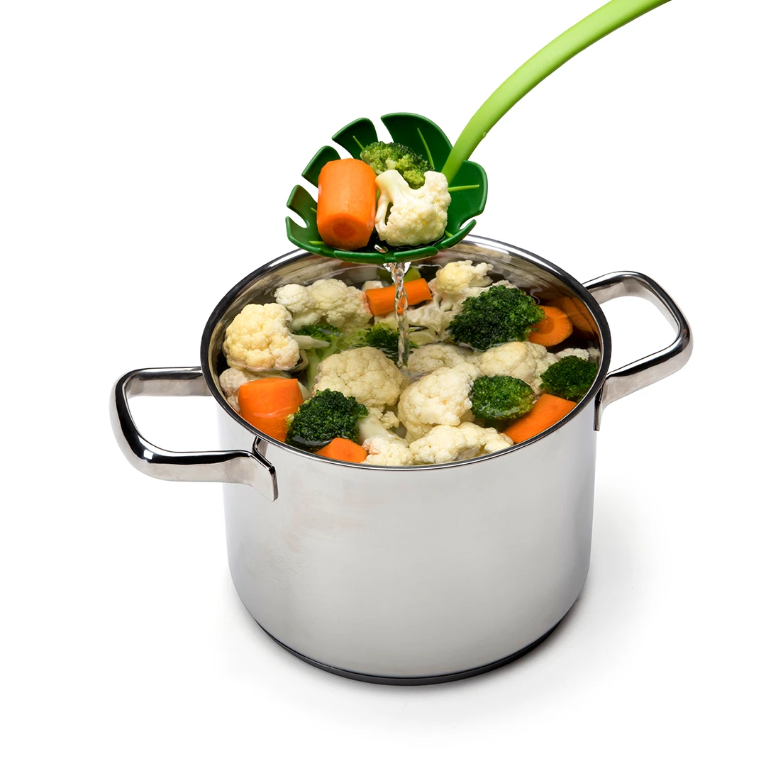 Steamed vegetables being strained from a pot using a green strainer spoon.