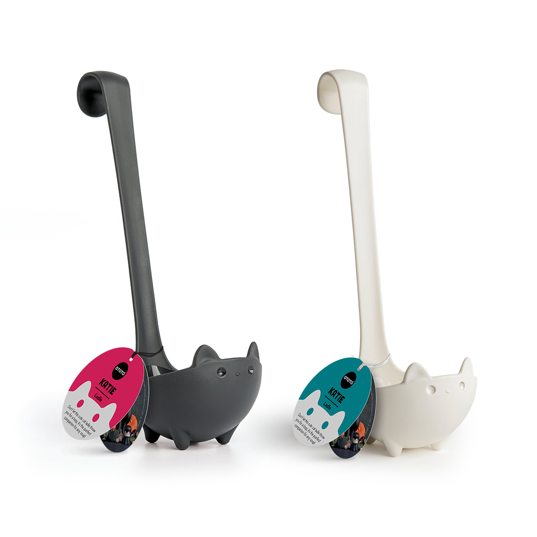 Two black and white OTOTO Katie cat-shaped ladles stand upright, with tags on the handles.