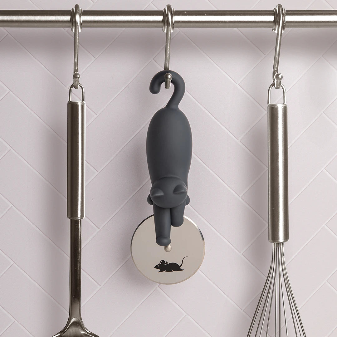 The OTOTO Kitty-Cut pizza cutter hangs on a rod, surrounded by kitchen utensils.