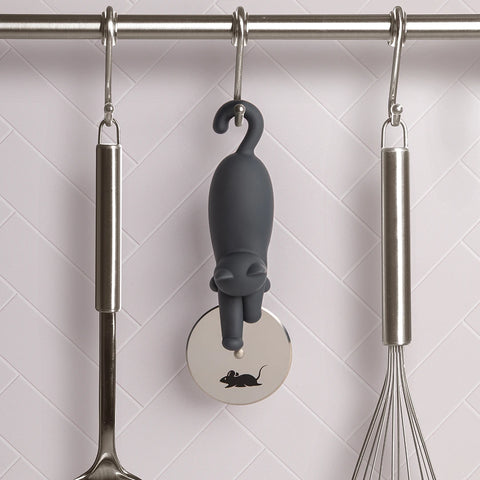The OTOTO Kitty-Cut pizza cutter hangs on a rod, surrounded by kitchen utensils.