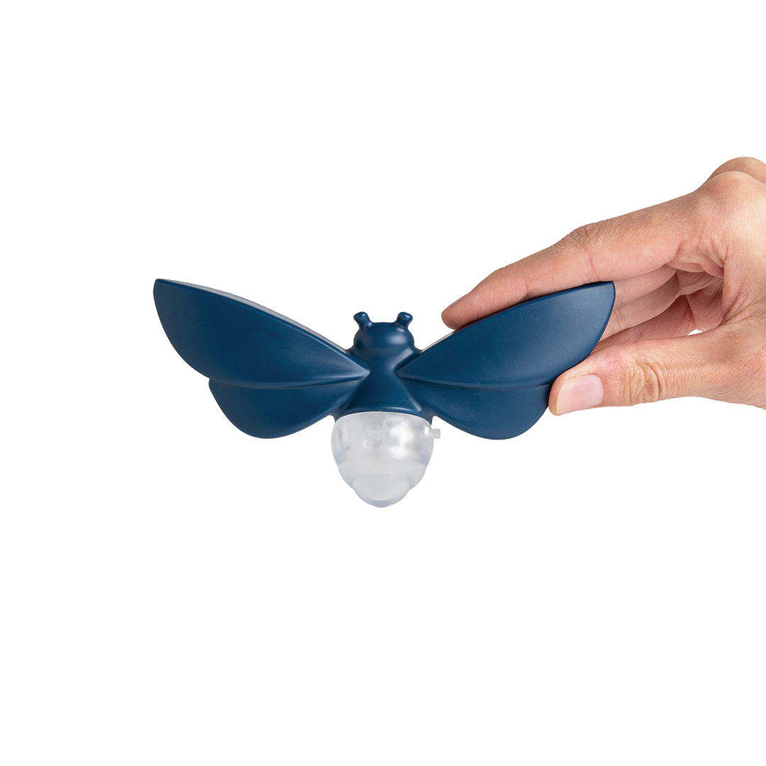 Hand holding a Lightbug night light in blue with a transparent bulb.
