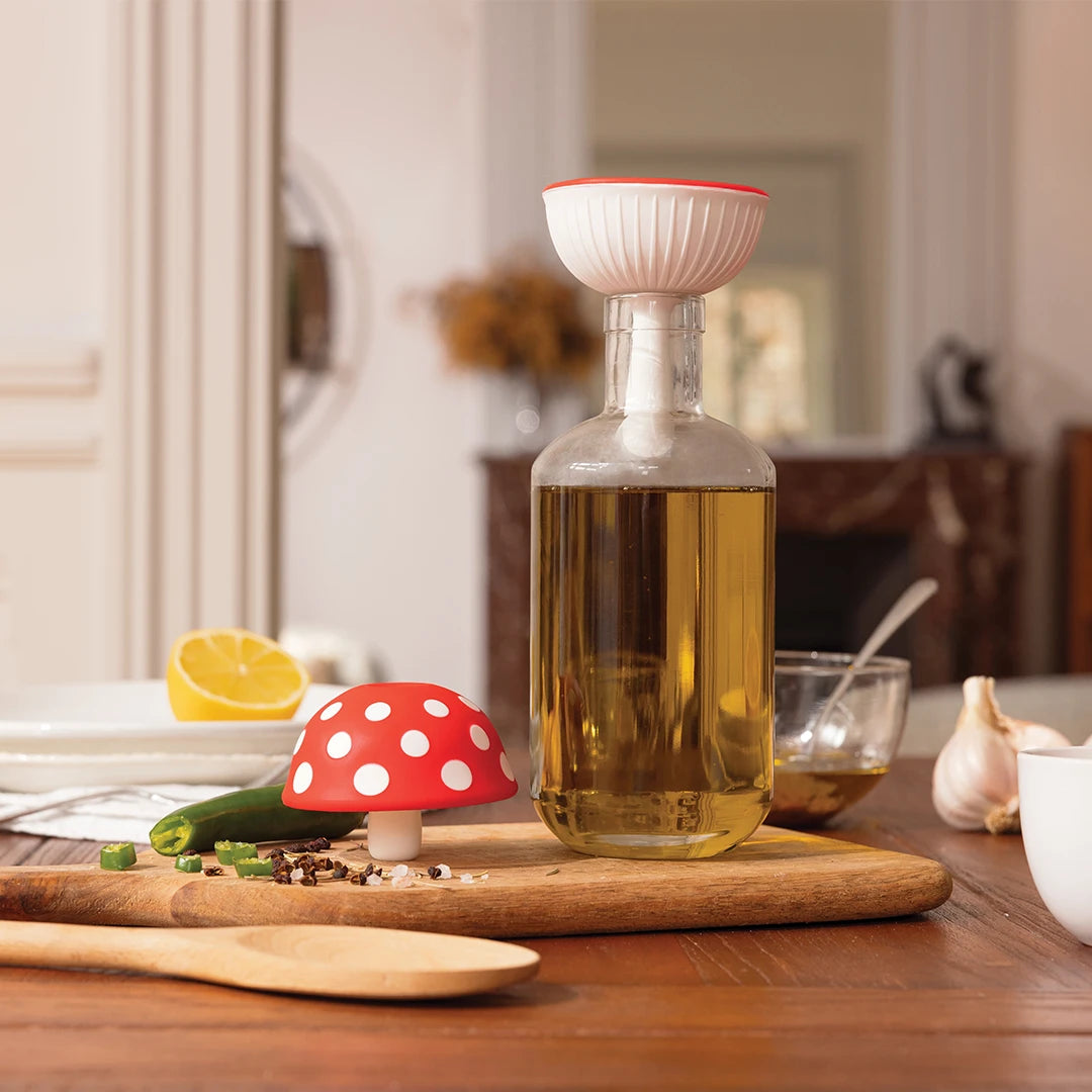 Fungilicious glass bottle by OTOTO, featuring a red mushroom-shaped stopper, amidst cooking ingredients.