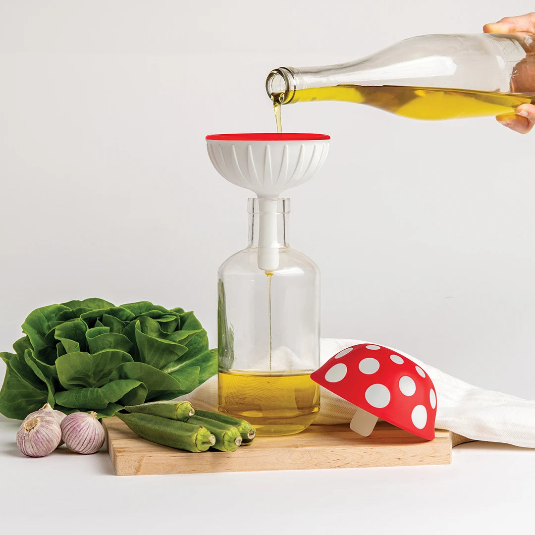 Oil poured into a bottle using the Fungilicious XL funnel with veggies on a wooden board.