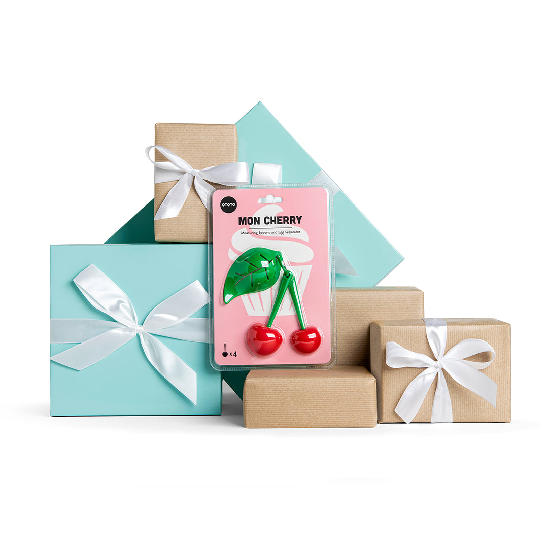 Mon Cherry gift boxes with white bows and a cherry-shaped corkscrew plus measuring spoons on white.