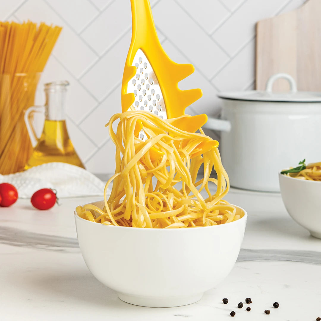 The Multi Monster lifts spaghetti from a bowl; kitchen items in the background.