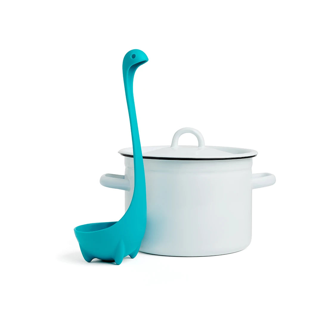 Nessie soup ladle in teal next to a white pot with handles and lid.