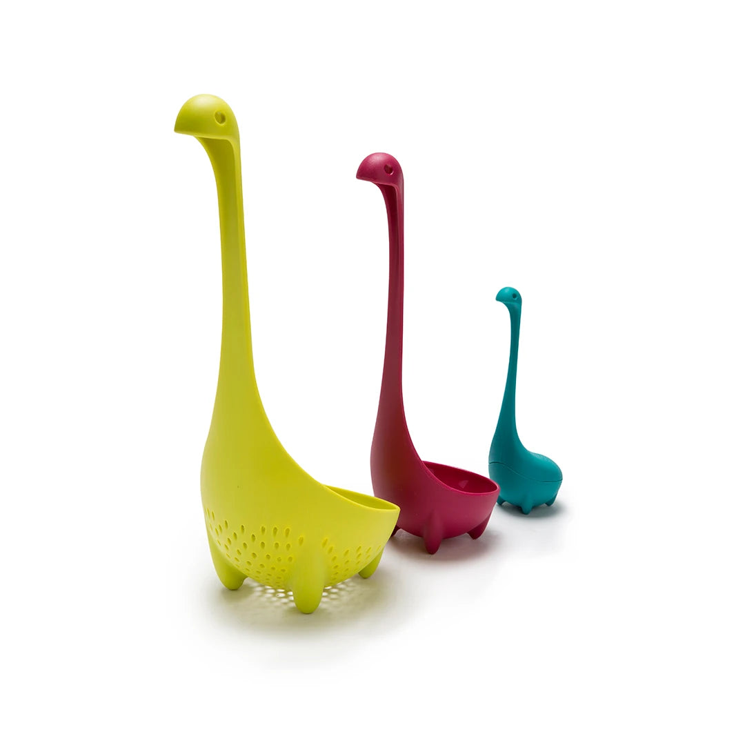 Meet the Nessie Family: dinosaur-shaped kitchen gadgets—a yellow colander, red ladle, and teal spoon.