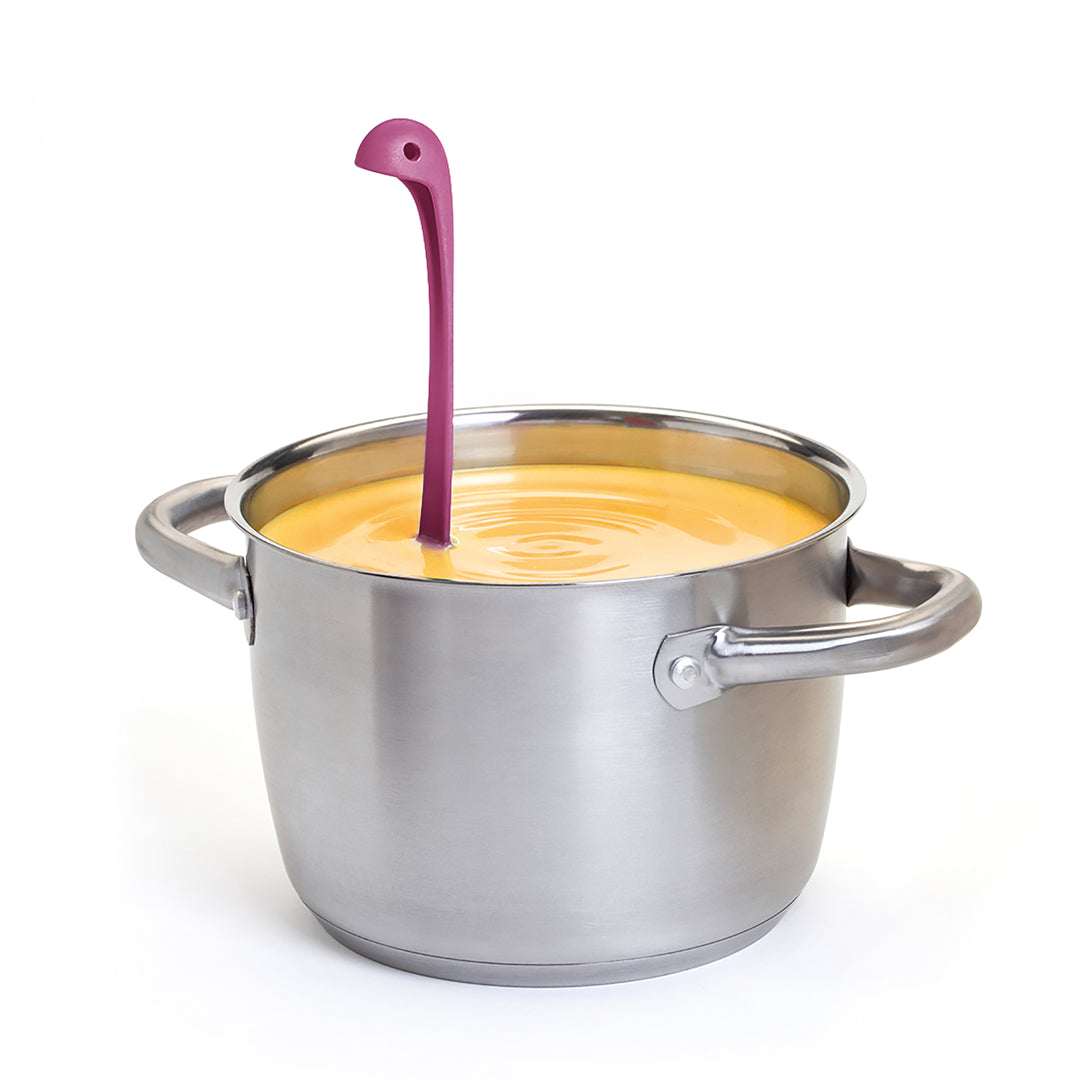 A pink ladle resembling a dinosaur standing in a pot of thick orange soup.