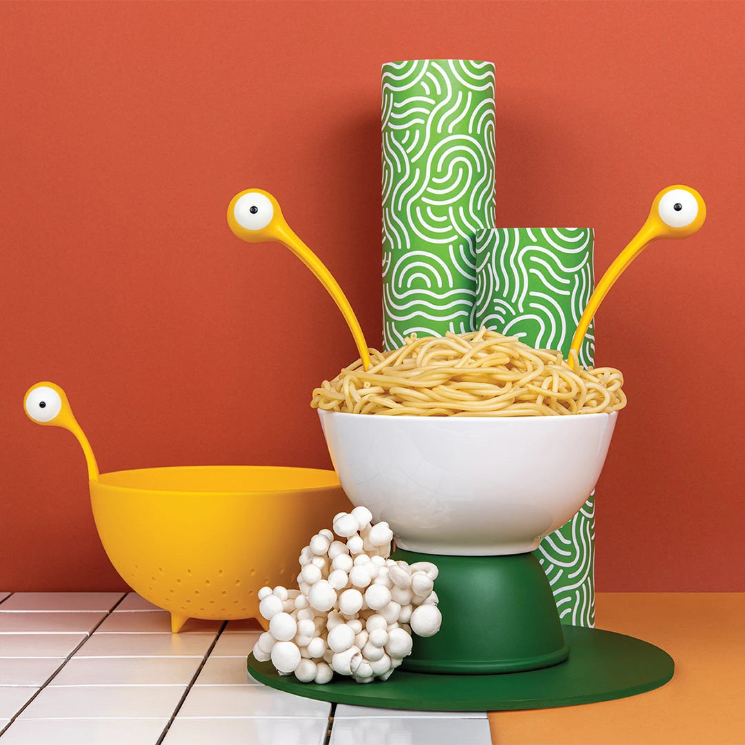 OTOTOs Pasta Monsters in a playful kitchen with spaghetti, mushrooms, and a yellow colander.