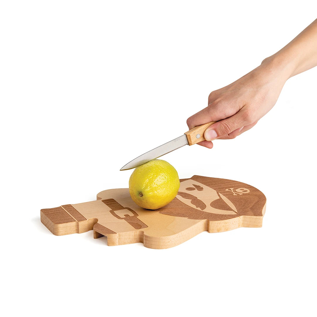 Hand slicing a yellow lemon on a Pirate Board from OTOTO shaped like a mans profile.