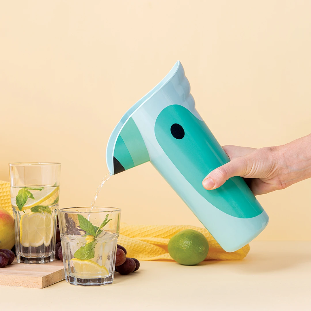 Person pours water from the Polly pitcher into a glass with lemon and mint.