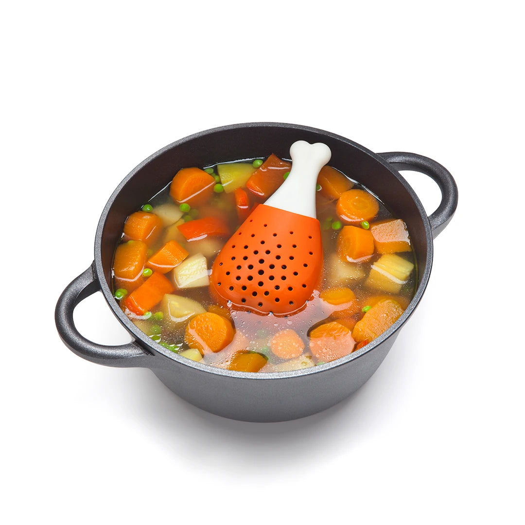 Pot of vegetable soup with an OTOTO Pulke, a drumstick-shaped herb infuser, floating on top.