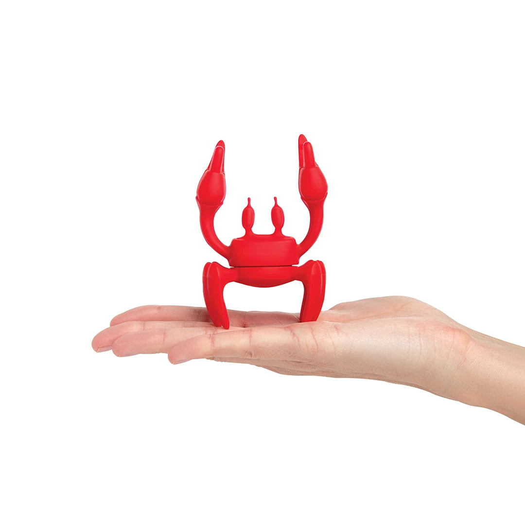 The OTOTO phone holder, Red, mimics a crab on a hand against a white backdrop.