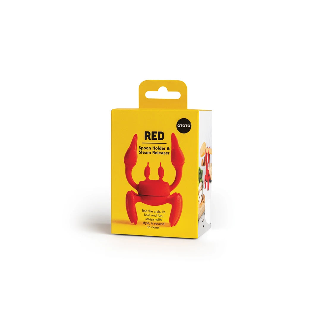 Yellow and white box with Red, an OTOTO crab-shaped red silicone utensil rest and steam releaser inside.