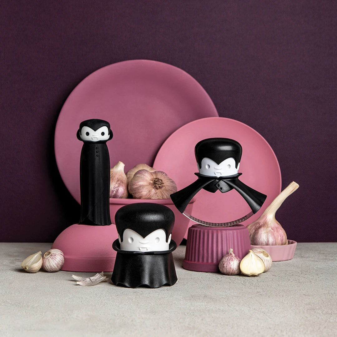 Rockula vampire gadgets, garlic crushers set against a purple and pink dishware backdrop.